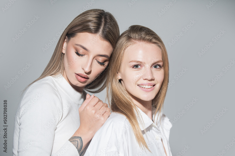 Portrait of two cheerful young women. Two beautiful young women with perfect skin in the studio. Lesbians lgbt couple. Portrait of two cheerful young women. Two beautiful young women with perfect skin in the studio. Lesbians lgbt couple.