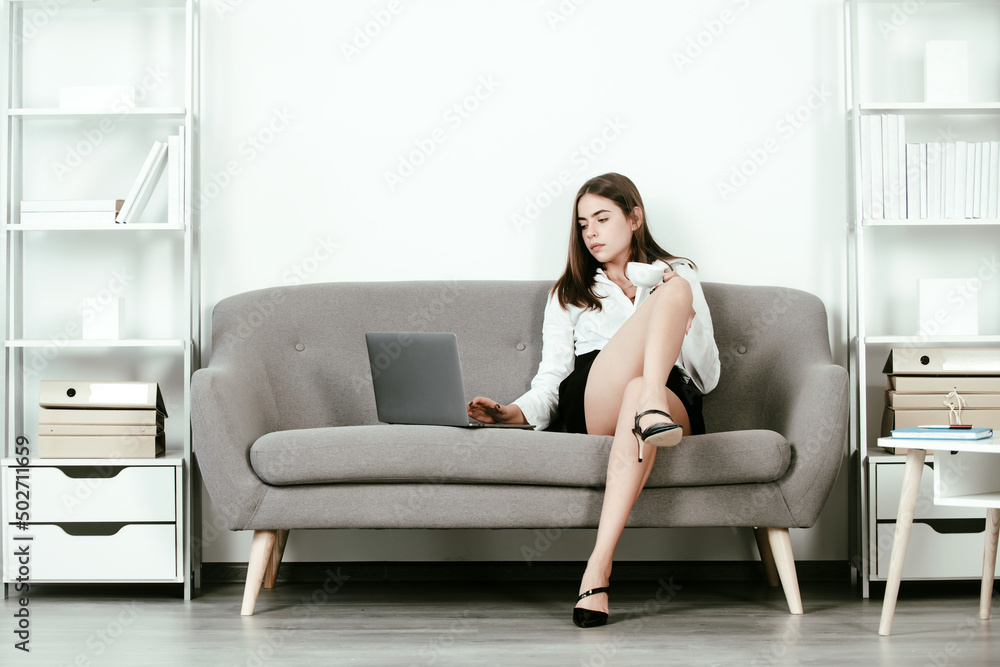 Young attractive sexy secretary with laptop in office. Pretty accountant sensual woman at desk in office interior. Sexy long legs. Young attractive sexy secretary with laptop in office. Pretty accountant sensual woman at desk in office interior. Sexy long legs.