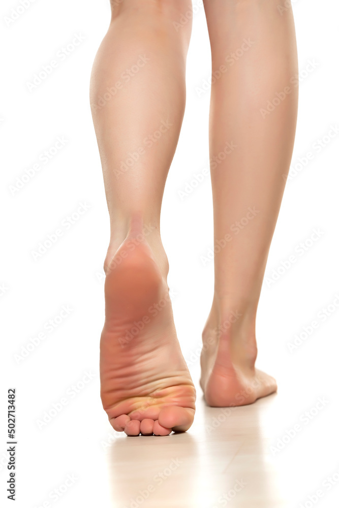 Slender beautiful female bare feet rear view on a white background Slender beautiful female bare feet rear view on a white background