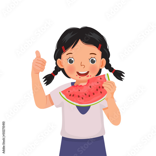 Cute little girl eating watermelon on sunny day in summertime showing thumb up