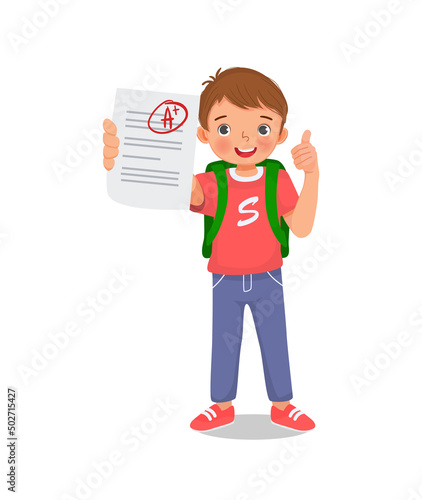 Happy little schoolboy holding exam paper with good mark A plus grade in test result showing thumb up gesture