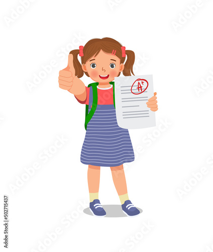 Happy little schoolgirl holding exam paper with good mark A plus grade in test result showing thumb up gesture