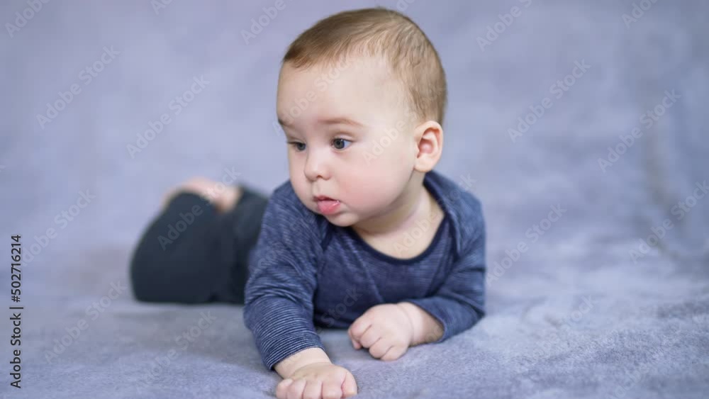 Lovely Caucasian child looks sideways with surprise. Astonished little kid watching something with an open mouth. Close up. Grey backdrop. Lovely Caucasian child looks sideways with surprise. Astonished little kid watching something with an open mouth. Close up. Grey backdrop.