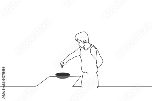man pouring seasoning into a frying pan on the stove - one line drawing vector. concept cooking at home, male cook prepares a dish