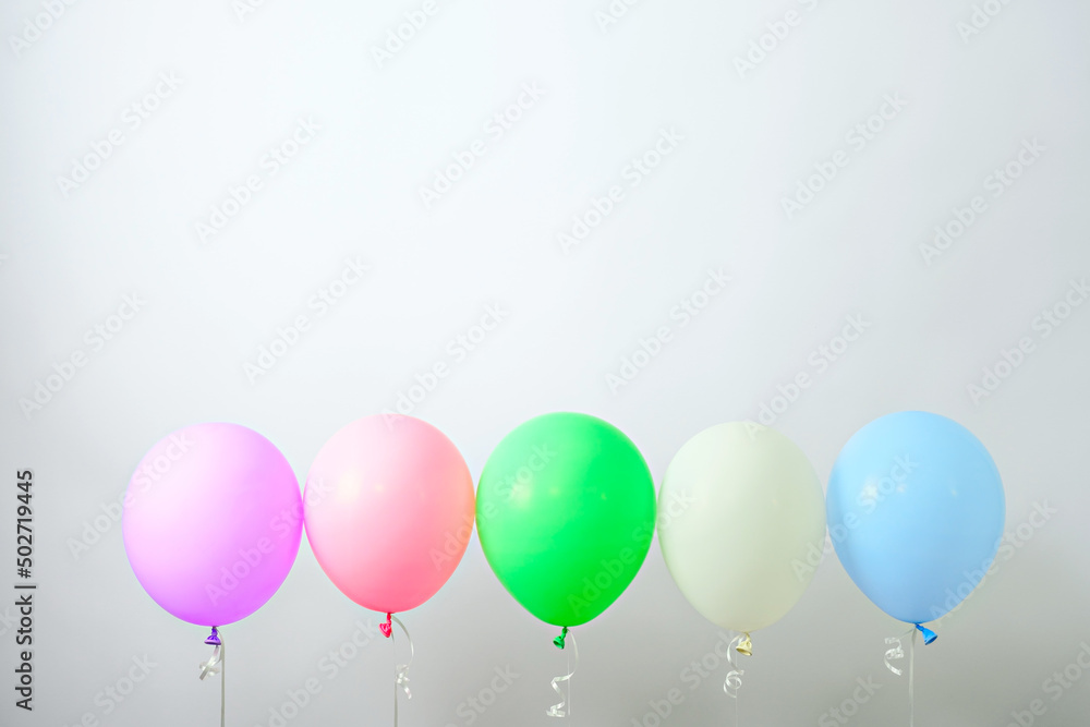 five multicolored helium balloons in row on white background for holiday