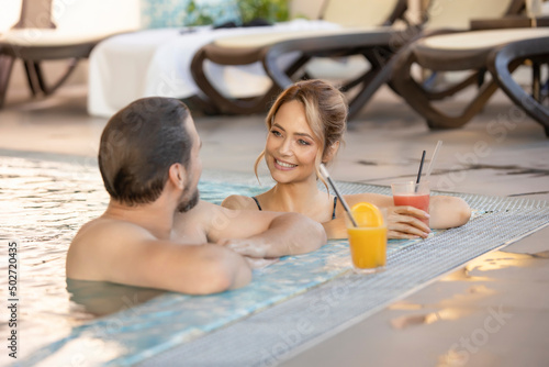 Foto Happy couple drinking juice in the indoor swimming pool