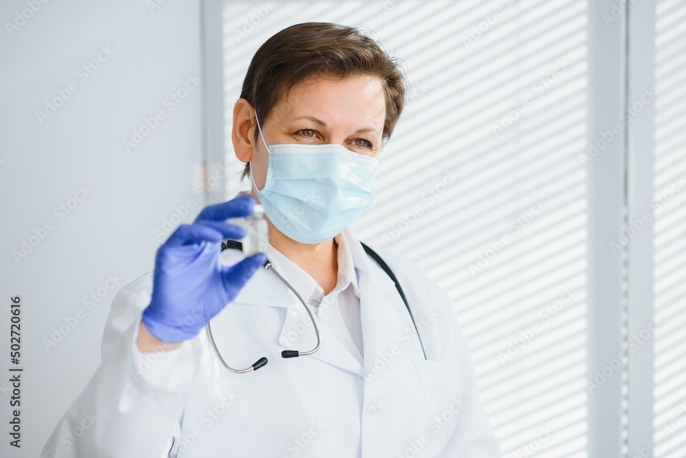 Portrait of a female doctor wearing face mask and holding her patient chart on digital tablet while standing at the hospital. Portrait of a female doctor wearing face mask and holding her patient chart on digital tablet while standing at the hospital.