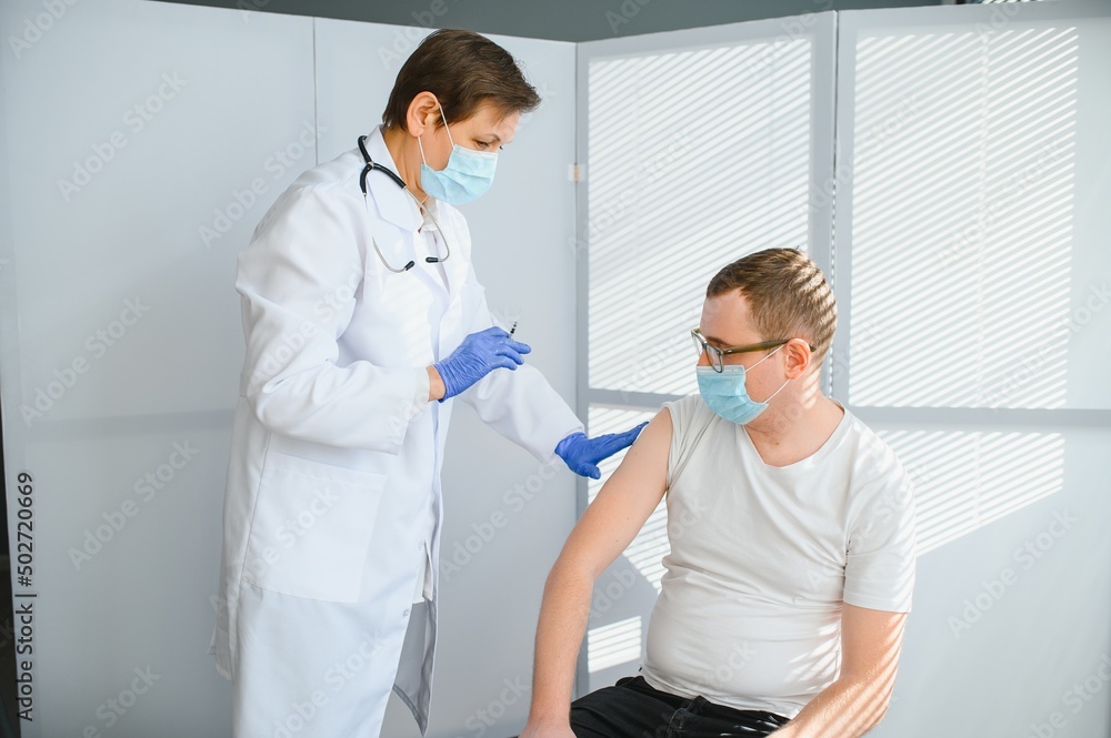 Obraz premium Close up of a Doctor making a vaccination in the shoulder of patient, Flu Vaccination Injection on Arm, coronavirus, covid-19 vaccine disease preparing for human clinical trials vaccination shot.