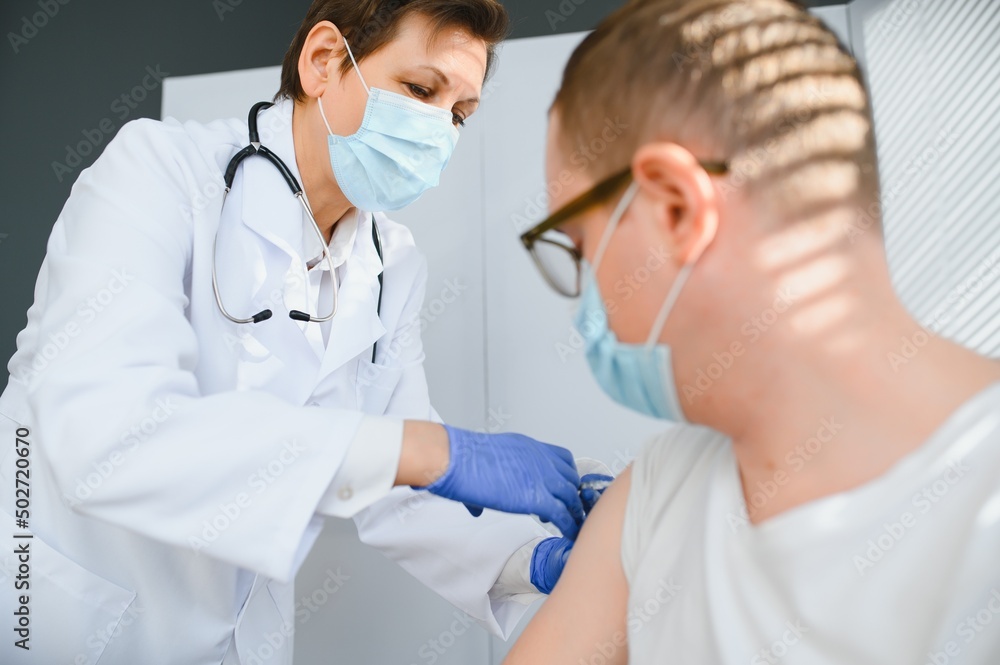 Female doctor making injecting using syringe to male patient in hospital. Senior man taking injection for flu in clinic. Female doctor vaccinating a man. Female doctor making injecting using syringe to male patient in hospital. Senior man taking injection for flu in clinic. Female doctor vaccinating a man.