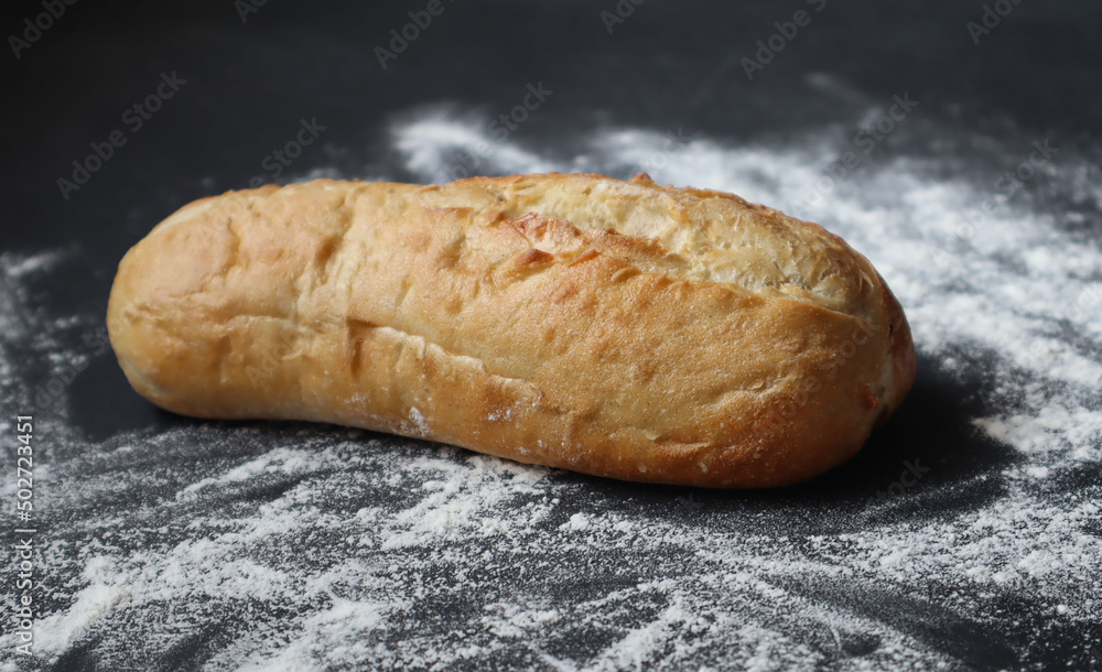golden loaf in flour on the table,close-up, rich bread Selective focus,bread in flour on a black background