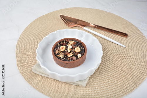 luxury home baked rocher dark rich chocolate tart in 3 layer with hazelnut mixed nuts and gold foil in white background halal dessert menu for hotel cafe photo