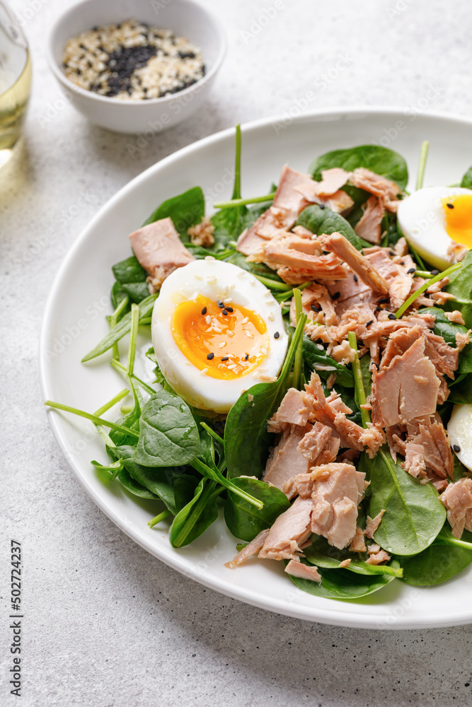 Close up Tuna salad with boiled egg and spinach on white plate. Keto diet, healthy food. Fresh vegetable salad bowl.