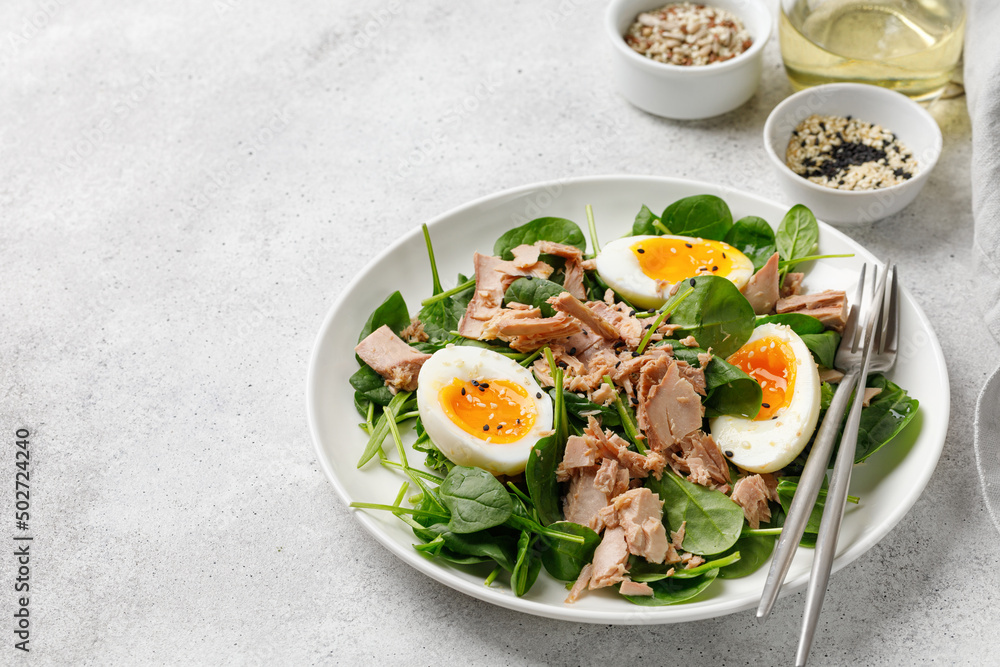 Tuna salad with boiled egg and spinach on white plate. Keto diet, healthy food. Fresh salad bowl. Dinner.