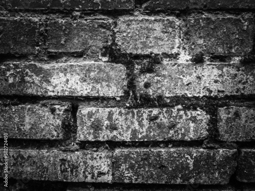 Old brickwork, a wall with dark spots and cracks. Black and white monochrome photography.