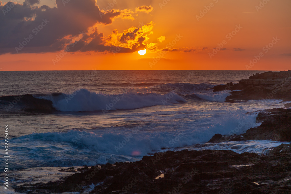 Obraz premium Bright beautiful stunning sea sunset, waves beating against the rocks in the rays of the setting sun