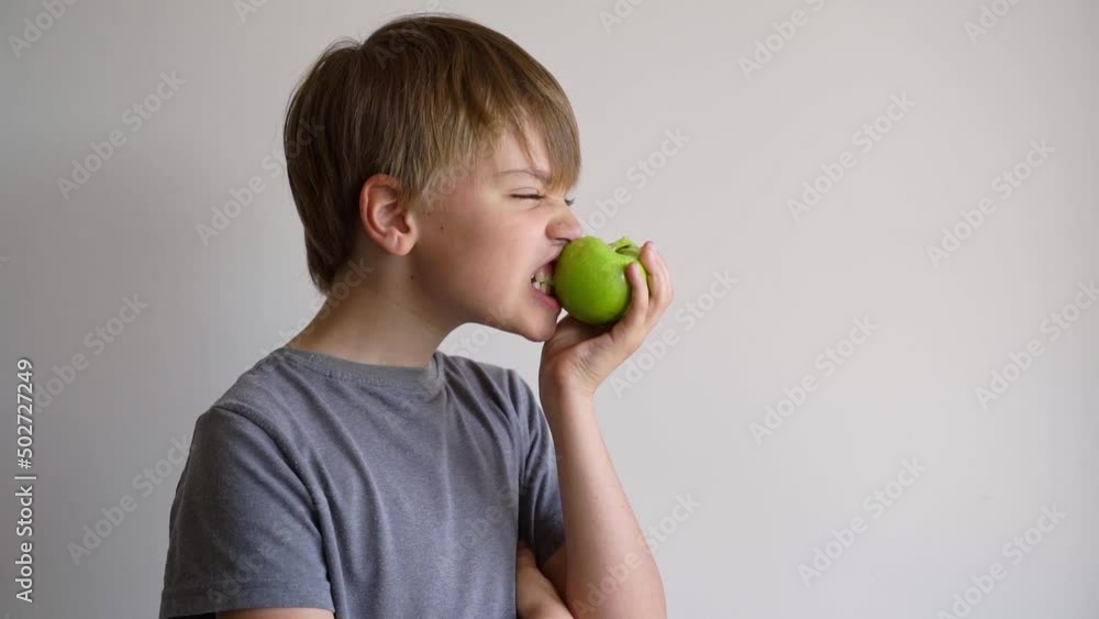 Child bites green apple, isolated over white background. Copy space. Child bites green apple, isolated over white background. Copy space.