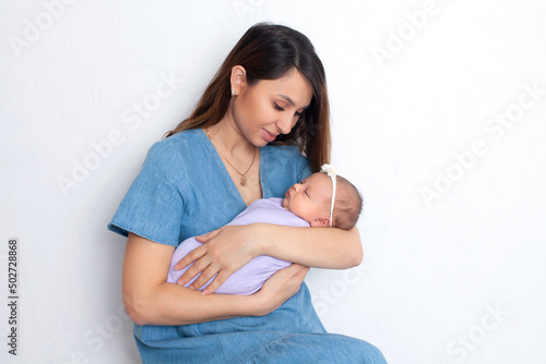 Beautiful young mother with a newborn daughter in a diaper on a white background. Motherhood. Tenderness. Space for text.