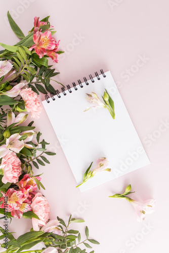Blank notepad with white sheets for your text on a light background with spring colors. top view. congratulations on the holidays.