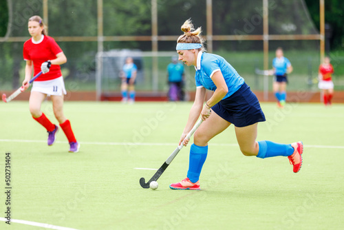Young woman field hockey player leading the ball in attack. © skumer