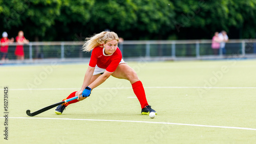 Young woman field hockey player hit the ball in attack on game.