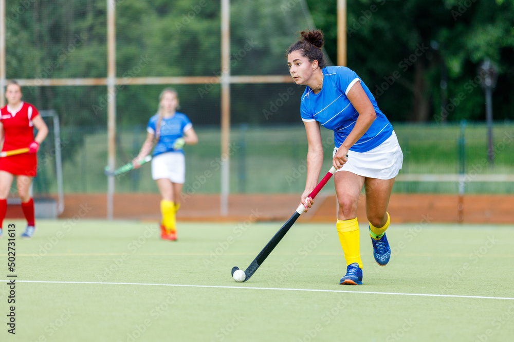 Young woman field hockey player leading the ball in attack.