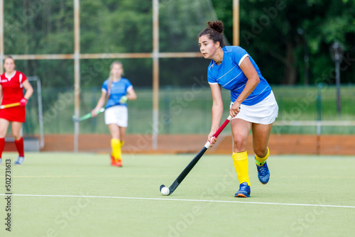 Young woman field hockey player leading the ball in attack.