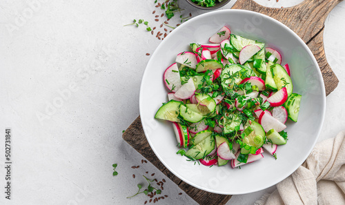 A healthy salad with radishes and herbs on a light background with a space to copy. Diet salad.
