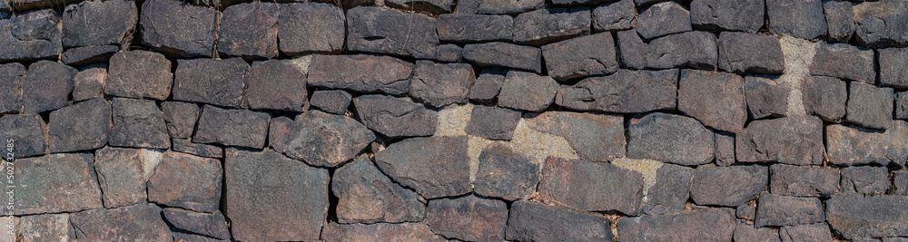Panoramic view over a long middle age stone wall with patterns of ancient bricks and stones as a background, closeup, details. Panoramic view over a long middle age stone wall with patterns of ancient bricks and stones as a background, closeup, details.