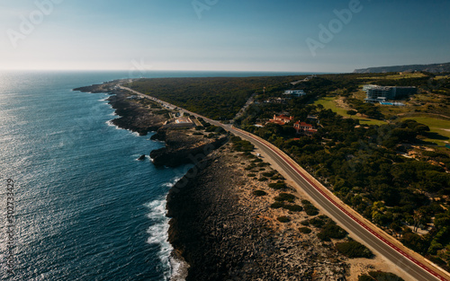 Aerial view top down view of of a straight road and rugged coastline at Guincho beach, Cascais, Portugal