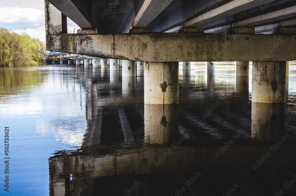 Curved concrete bridge across the river. Spring flood of the river.