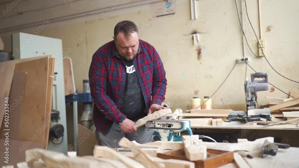 A carpenter stands in his workshop and works with wood on an electric grinder A carpenter stands in his workshop and works with wood on an electric grinder