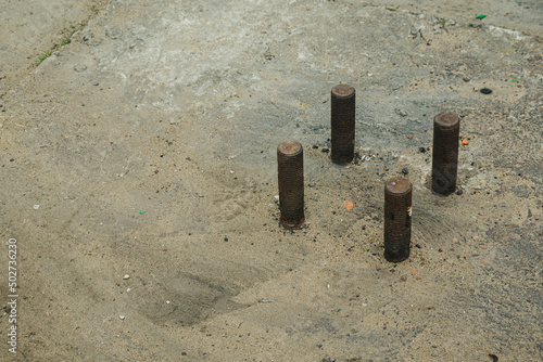 Fotografia Four metal fasteners protrude from reinforced concrete