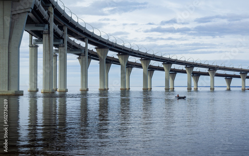 A man on a motorboat passes under a road bridge © Alexander