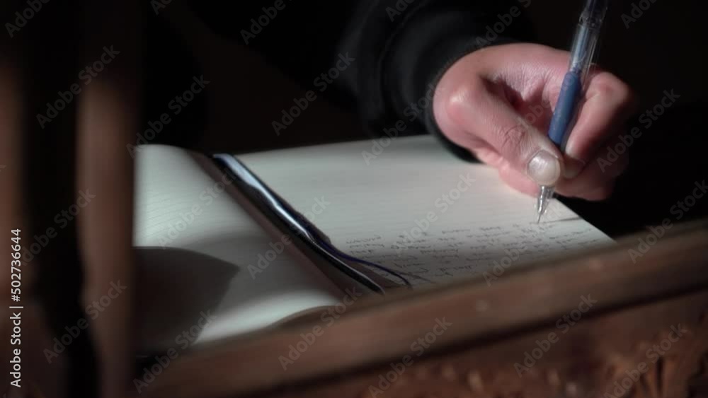 Close up of a person's hand journaling in a book with a pencil and pen, shot through the refection of the mirror in morning light Close up of a person's hand journaling in a book with a pencil and pen, shot through the refection of the mirror in morning light