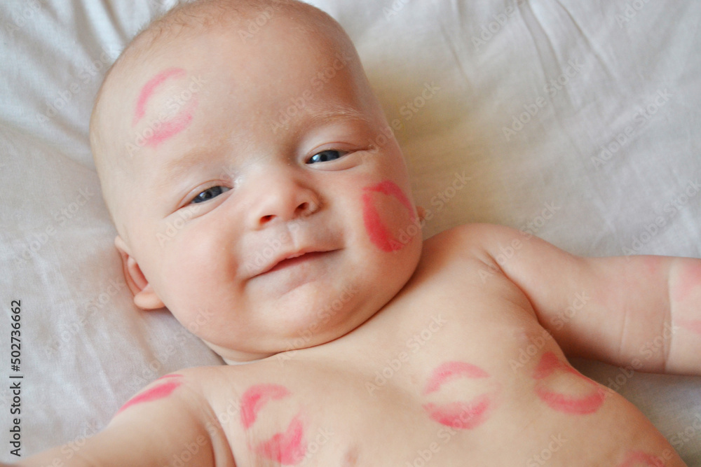 The image of a charming child with red kisses on the skin, a happy boy isolated on a white background, a little angel of love, a romantic holiday, the concept of Valentine's day The image of a charming child with red kisses on the skin, a happy boy isolated on a white background, a little angel of love, a romantic holiday, the concept of Valentine's day