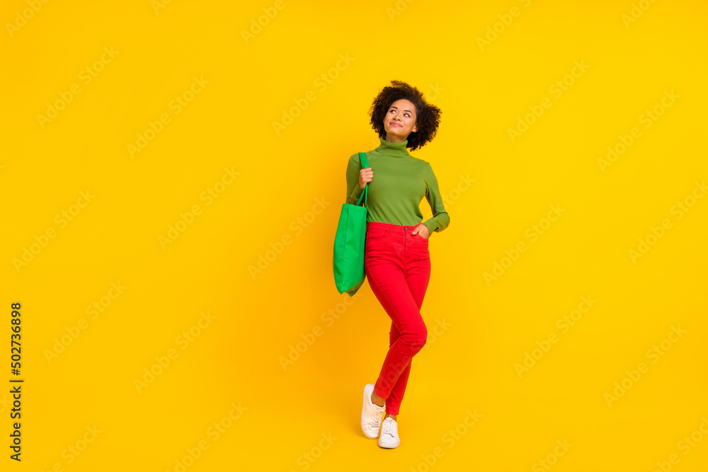 Full body photo of young cheerful girl dream think curious look empty space shopping isolated over yellow color background