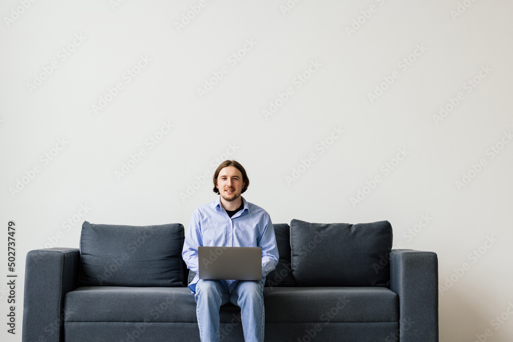 Young man working on laptop on the couch Young man working on laptop on the couch