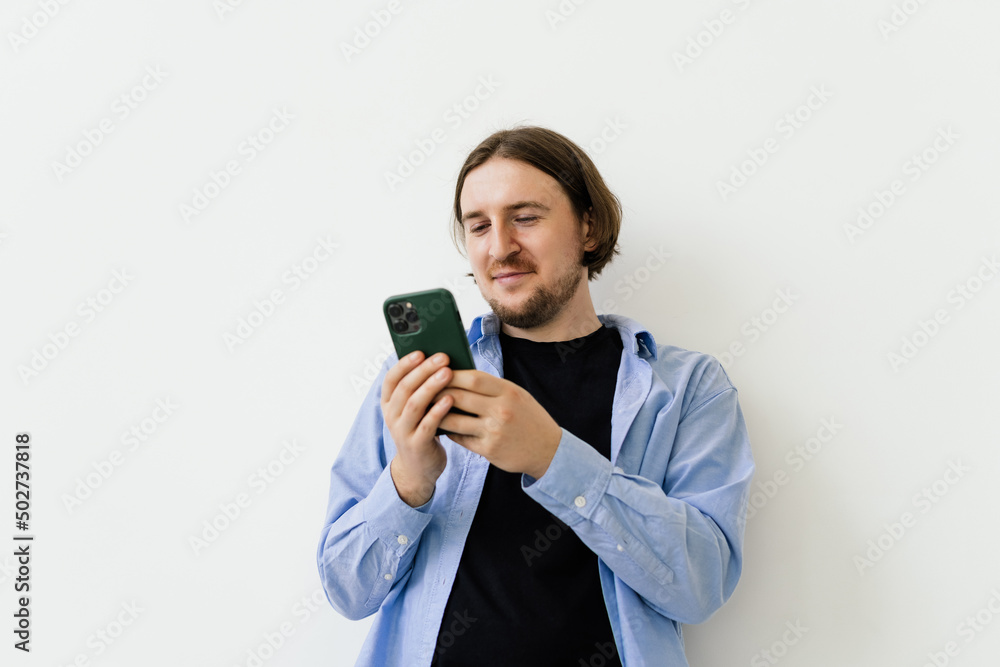 Young smiling businessman watching something on mobile phone isolated on white background. Studio shoot. Copy space Young smiling businessman watching something on mobile phone isolated on white background. Studio shoot. Copy space