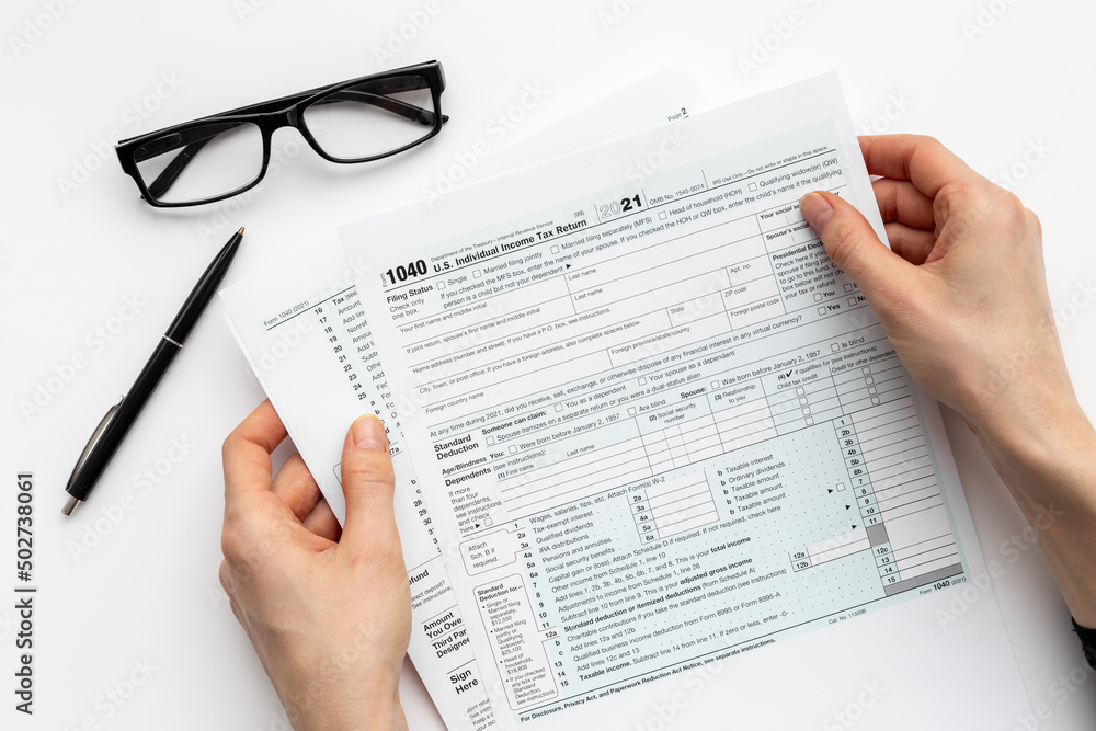 Obraz premium Hands filling US tax form. Culculating and payment of taxes concept