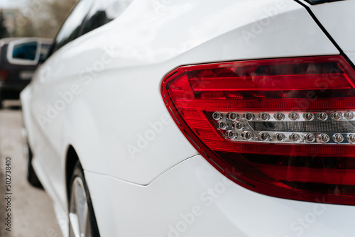 Rear red headlight of white modern car sedan parked on street. Close-up, back view