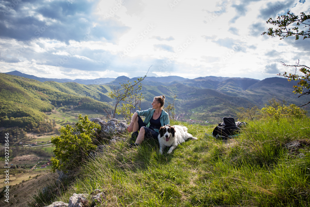 woman trekking in summer landscape with dog