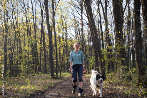 woman trekking in forest with dog