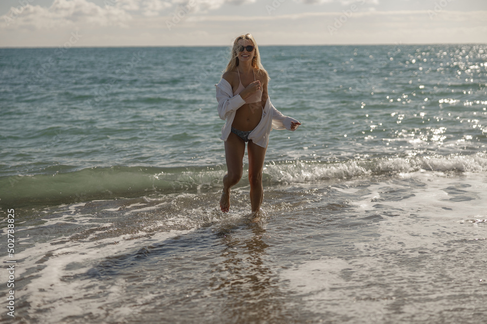 Young woman laughing while standing in sea water on summer vacation Young woman laughing while standing in sea water on summer vacation