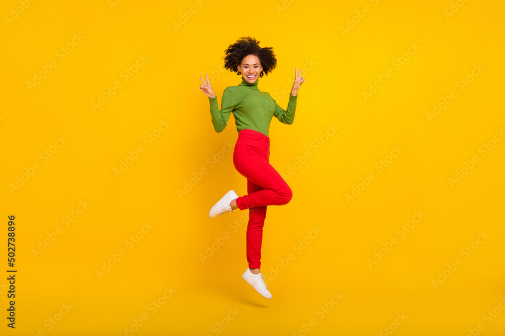 Full length profile side photo of young excited lady show fingers peace v-symbol jump energetic isolated over yellow color background