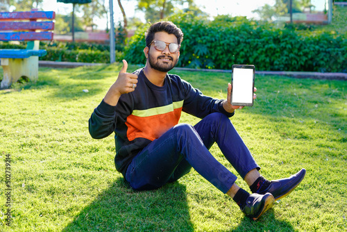Young indian man using smart phone in park.