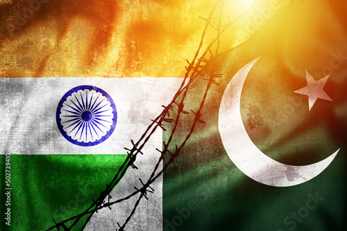 Grunge flags of India and Pakistan divided by barb wire sun haze illustration