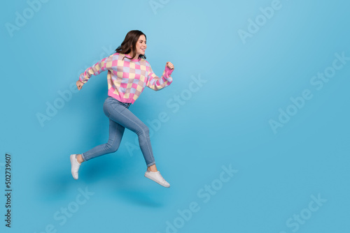 Full size photo of young pretty lady runner jumper hurry fast movement isolated over blue color background