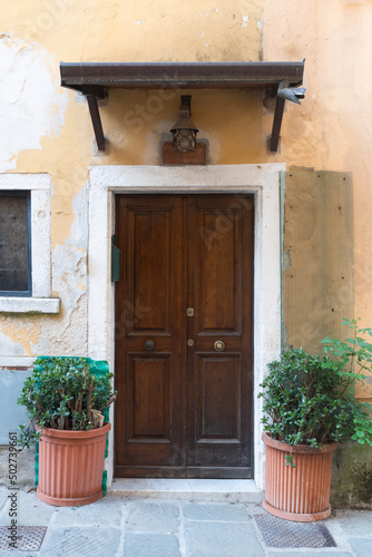Ancient door of an Italian house with marble portal and canopy