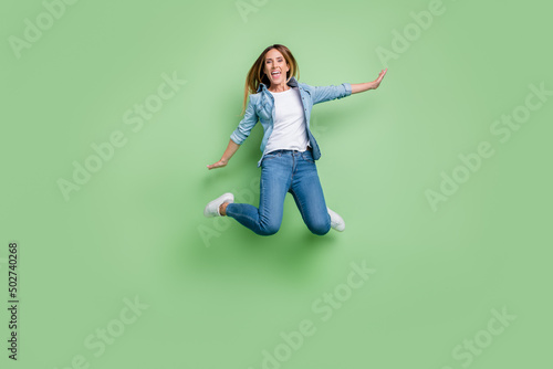 Full body photo of young lady jump wear shirt jeans footwear isolated on green background