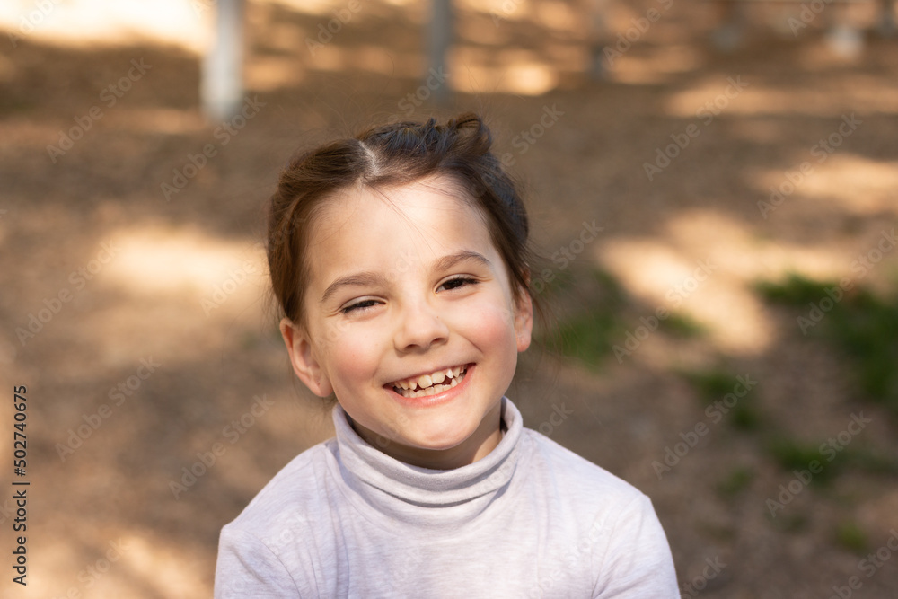 Close-up portrait of a little cute girl in a turtleneck sweater outdoors